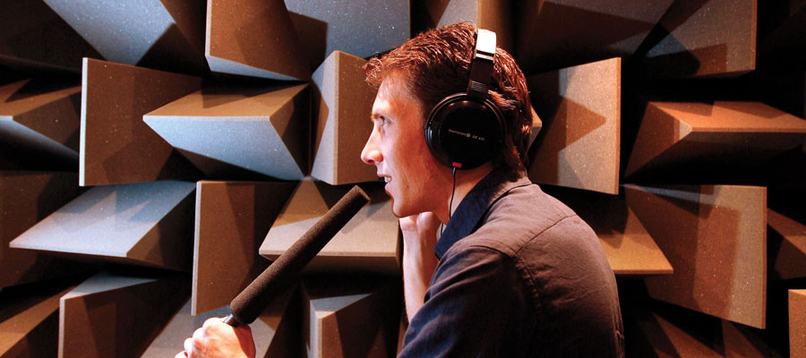 Man speaking into a mic in the University's near-anechoic chamber